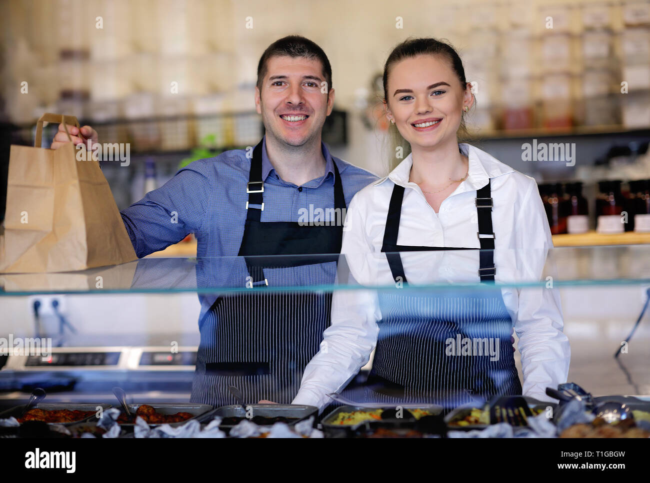 Jeune homme et femme debout derrière le comptoir d'un restaurant. Derrière la cuisine Banque D'Images