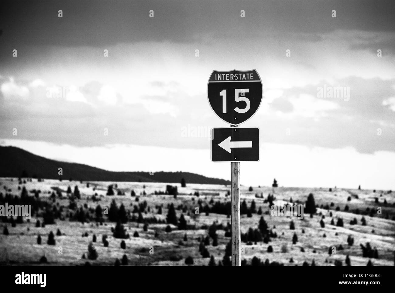 Une vue spectaculaire sur une autoroute Interstate 15 panneau avec une flèche dans le sud-ouest du Montana en noir et blanc contre un paysage stark Banque D'Images