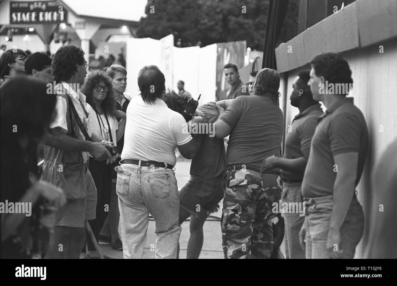 Les concerts sont présentés le personnel de sécurité de la suppression d'un mécène indisciplinés pendant un concert en plein air les performances. Banque D'Images