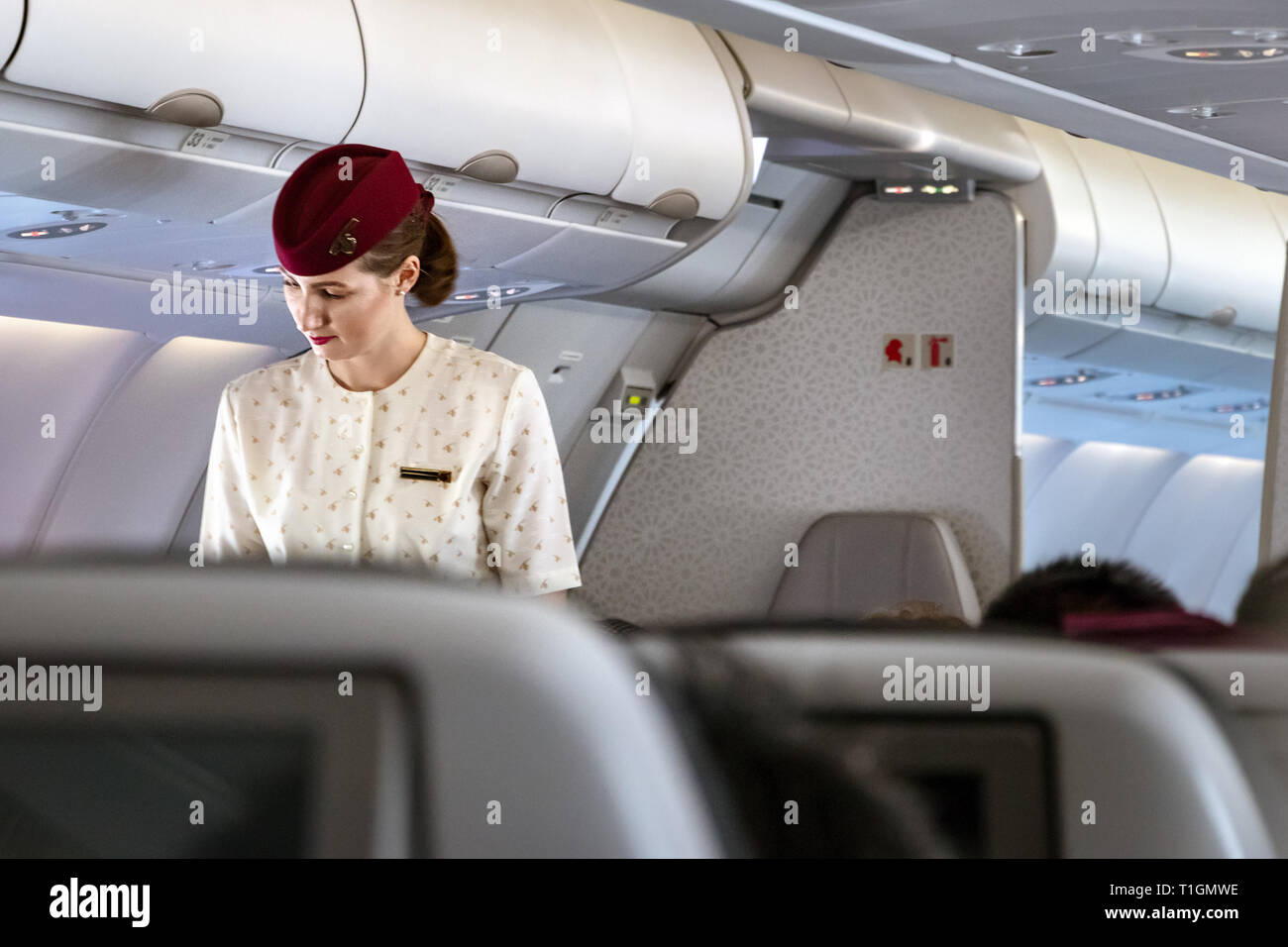 Doha, Qatar - Février 20th, 2019 : une femme parlant de bord de l'équipage de cabine avec un passager à bord de l'Airbus A350 de Qatar Airways. Banque D'Images