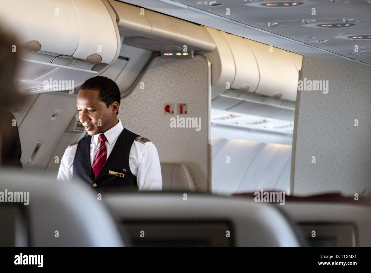 Doha, Qatar - Février 20th, 2019 : Un homme parlant de bord de l'équipage de cabine avec un passager à bord de l'Airbus A350 de Qatar Airways. Banque D'Images