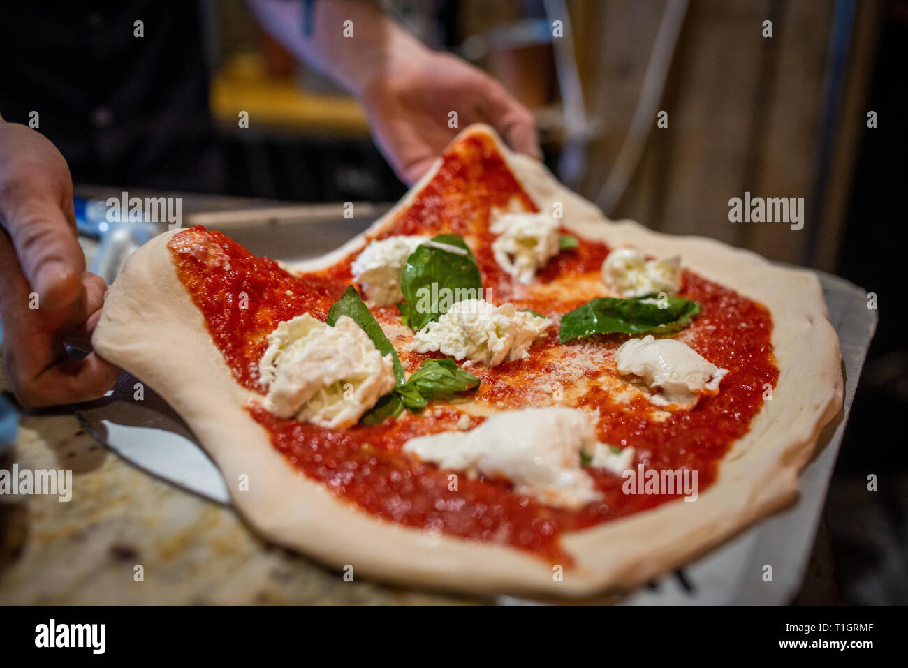 Close up of a chef's hands préparer une authentique pizza Margherita napolitain italien dans une pizzeria trattoria. Placer la pizza sur peel Banque D'Images