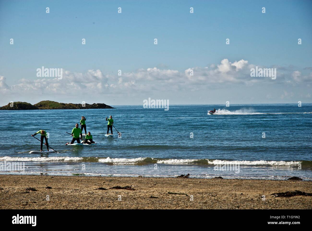 La plage approche chiffres lointain sur paddle boards, conseil informatique, Anglesey, au nord du Pays de Galles, Royaume-Uni Banque D'Images