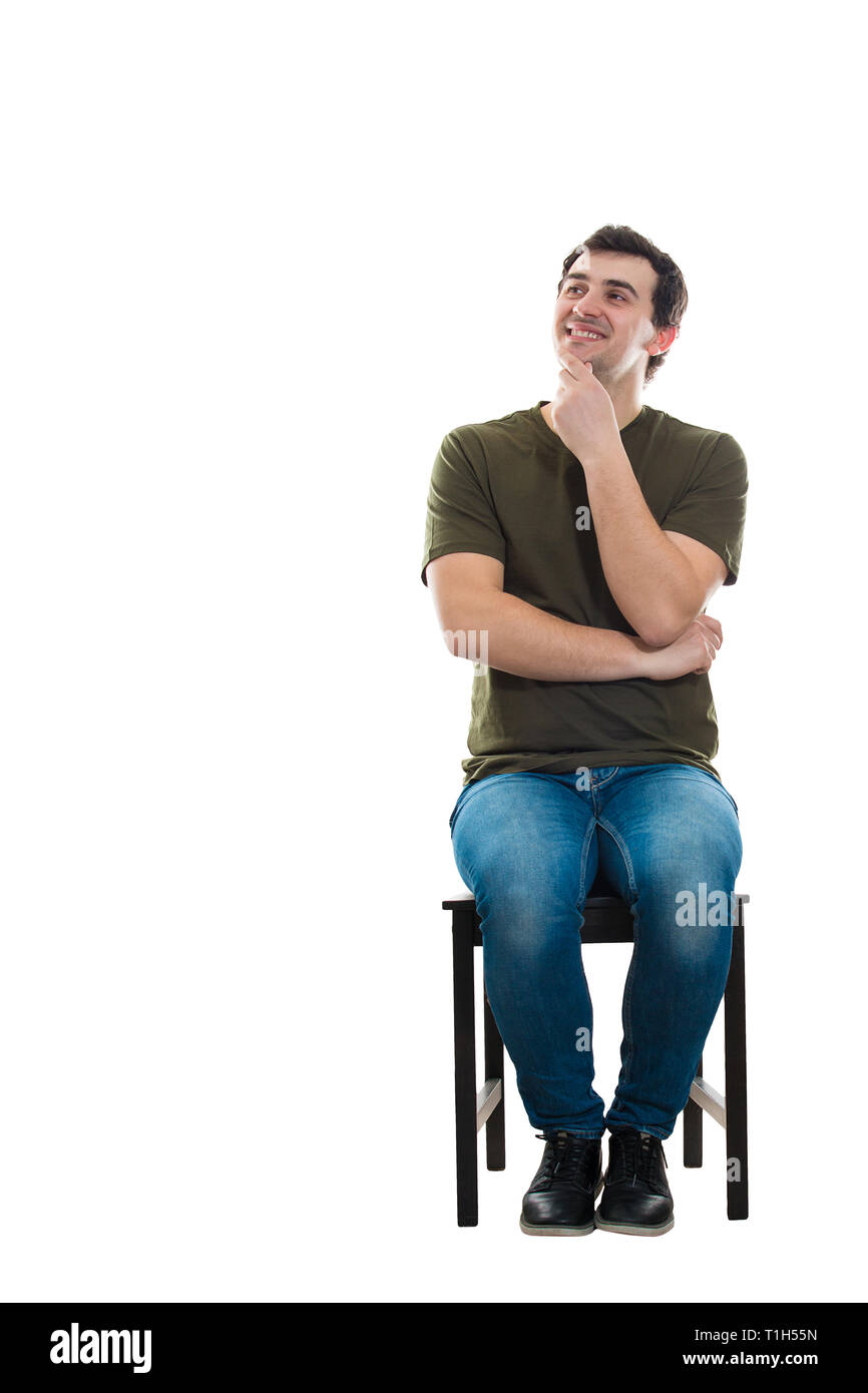 Portrait de jeune homme décontracté assis sur une chaise garde la main sous le menton à côté isolé sur fond blanc réfléchi avec spa de copie Banque D'Images