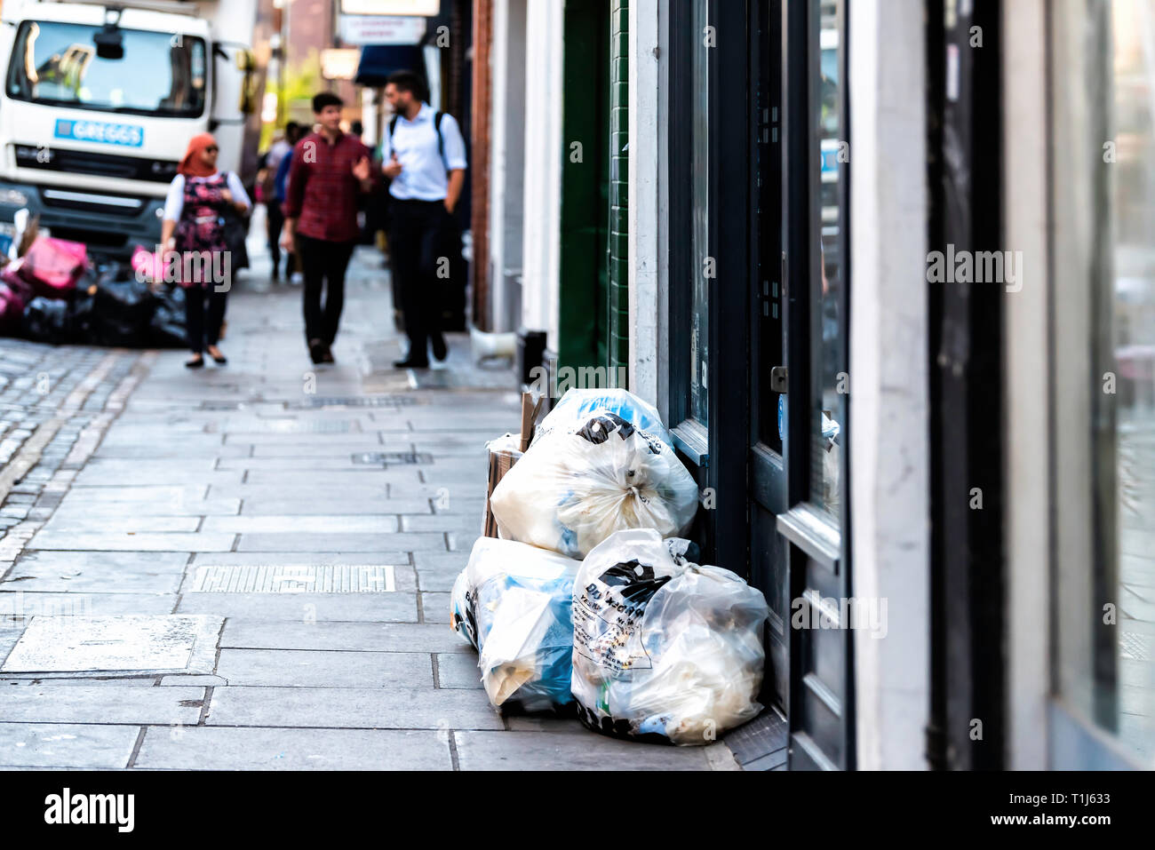 Londres, Royaume-Uni - 22 juin 2018 : People walking on street par beaucoup de sacs poubelle en plastique sur route avec des camions de livraison et Greggs sign Banque D'Images