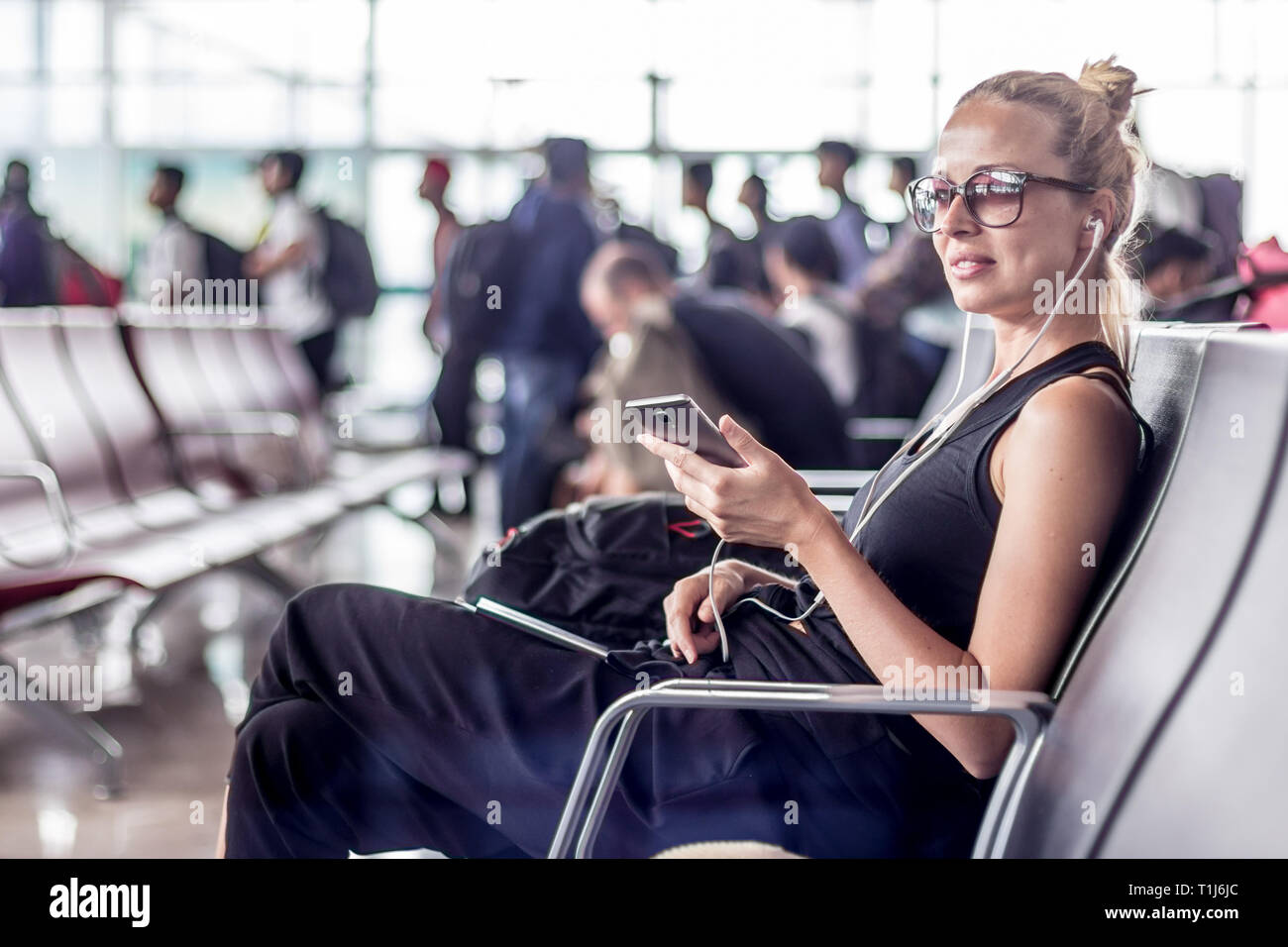 Female traveler talking on cell phone en attendant de monter à bord d'un avion à l'embarquement au terminal de l'aéroport d'Asie. Banque D'Images