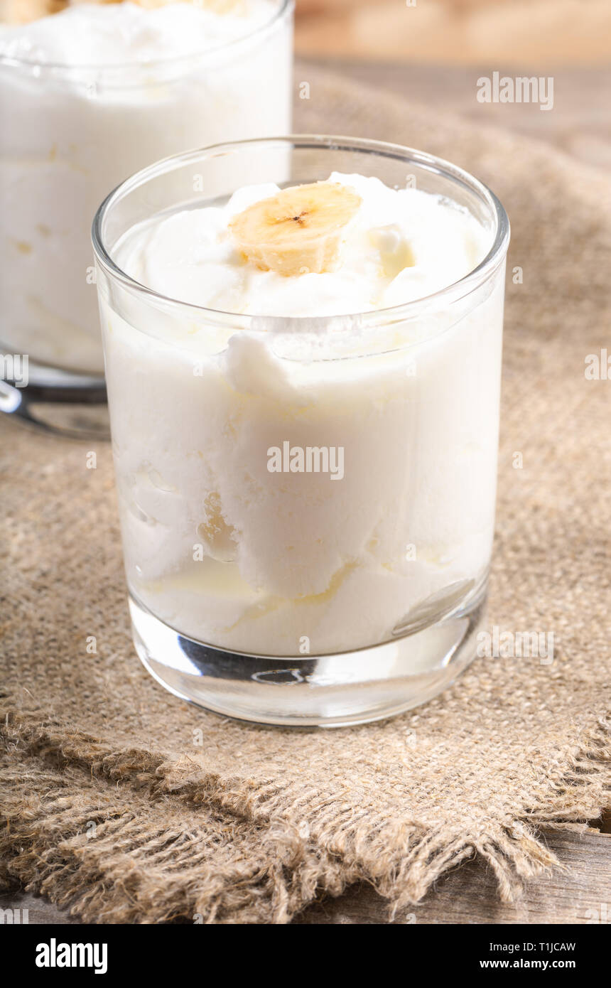 Yogourt maison traditionnelle avec des tranches de banane en verres transparents sur la serviette de toile. Banque D'Images