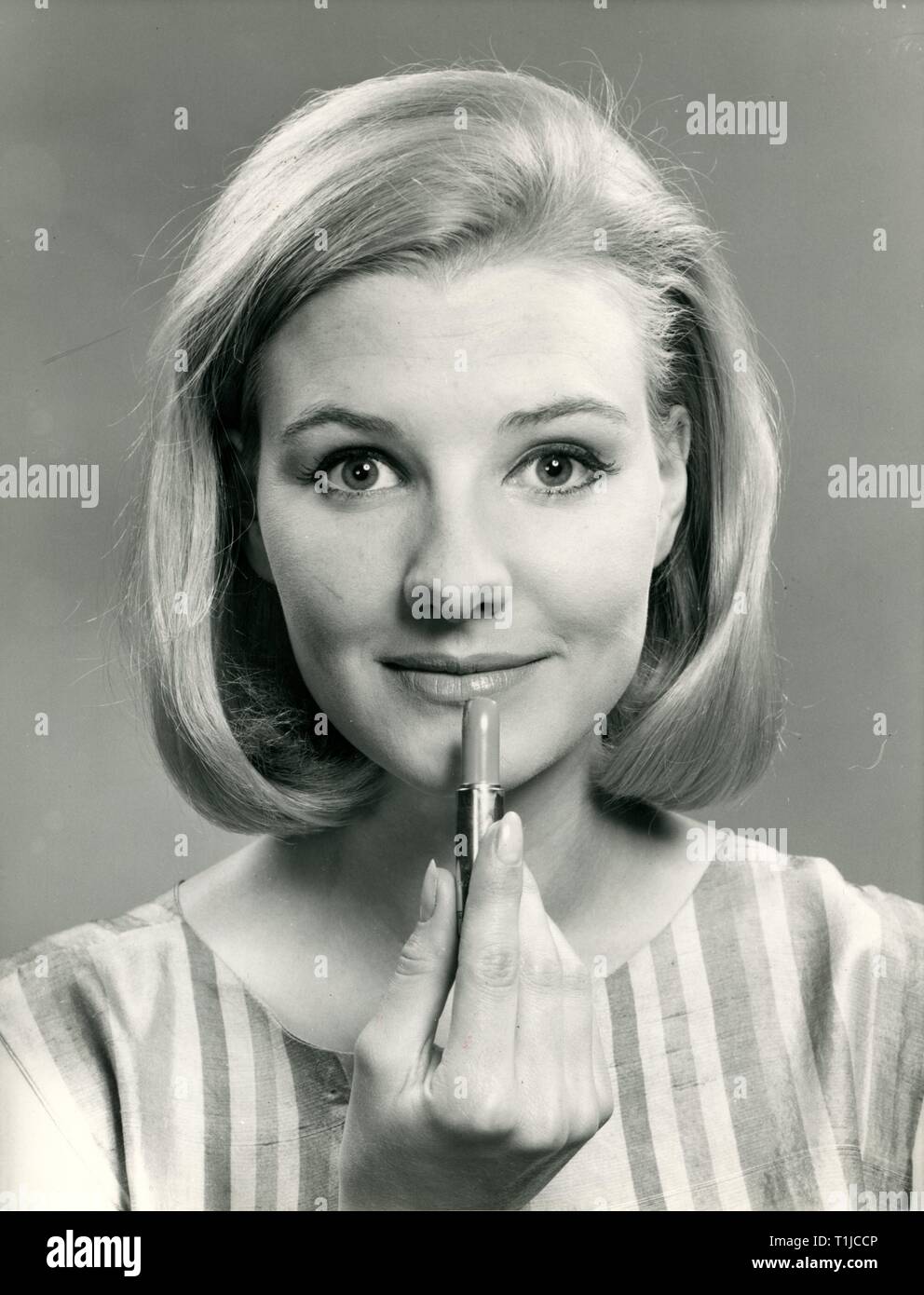 Les produits cosmétiques, young woman applying lipstick, 1960 Additional-Rights Clearance-Info-Not-Available- Banque D'Images