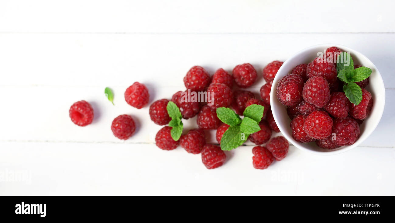 Framboises fraîches avec des feuilles de menthe sur fond blanc Banque D'Images