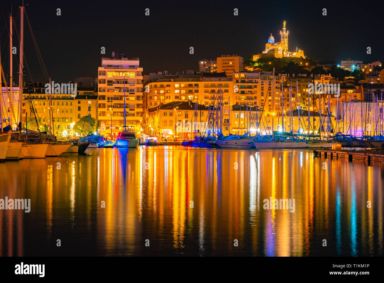 Marseille, France la nuit. Le célèbre port européen sur la Notre Dame de la Garde avec reflet dans l'eau coloré Banque D'Images