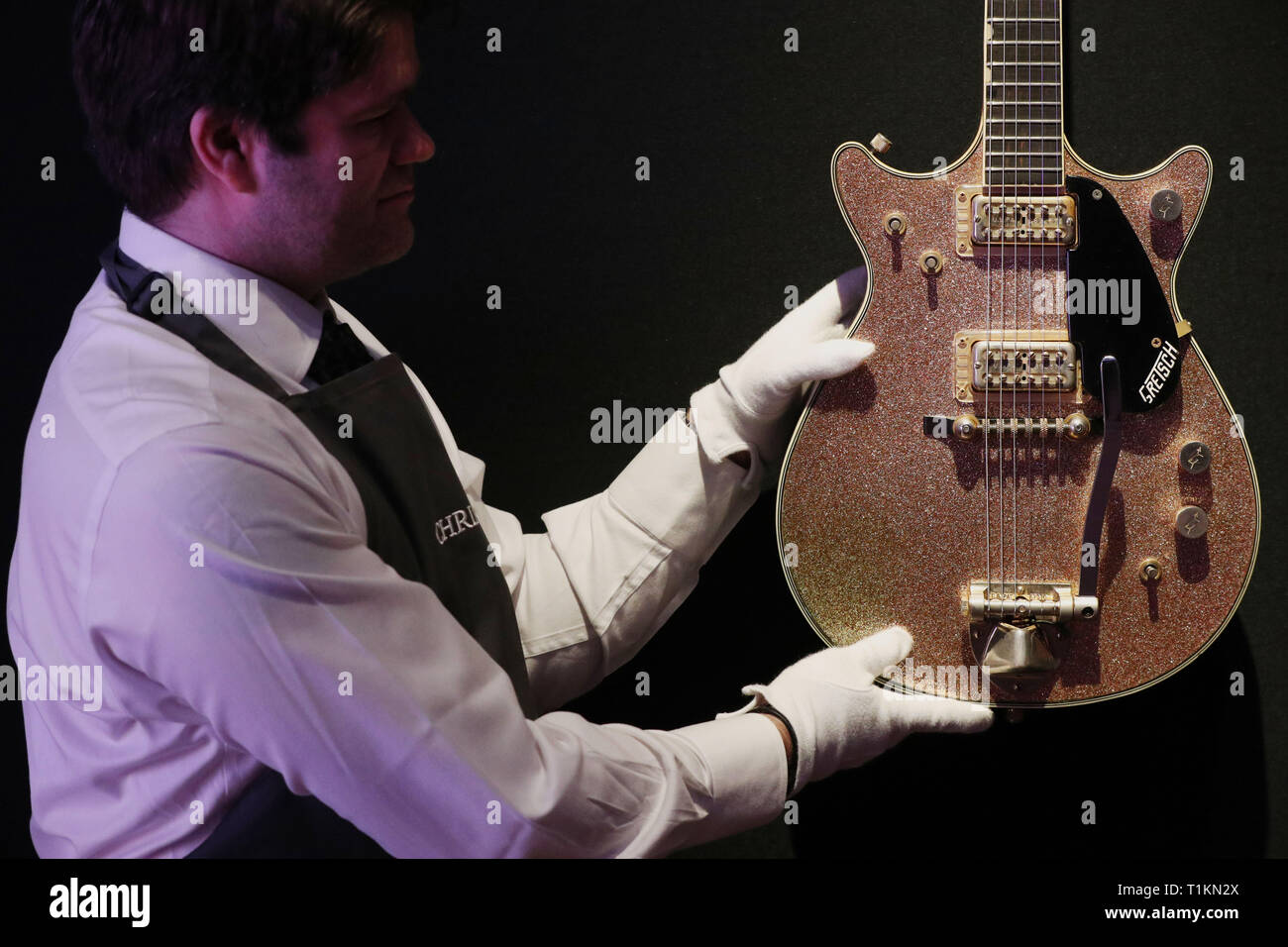 Un manutentionnaire saisit une Gretsch 1963 Champagne Duo-guitare électrique solid body jet lors d'un aperçu de l'exposition préalable à la vente de la collection de guitare personnels de Pink Floyd David Gilmour, chez Christie's à Londres. Banque D'Images