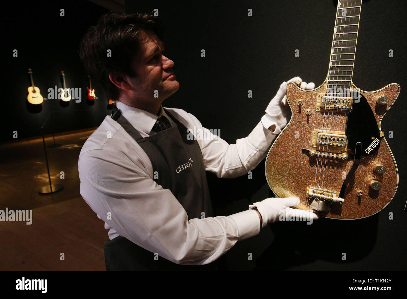 Un manutentionnaire saisit une Gretsch 1963 Champagne Duo-guitare électrique solid body jet lors d'un aperçu de l'exposition préalable à la vente de la collection de guitare personnels de Pink Floyd David Gilmour, chez Christie's à Londres. Banque D'Images