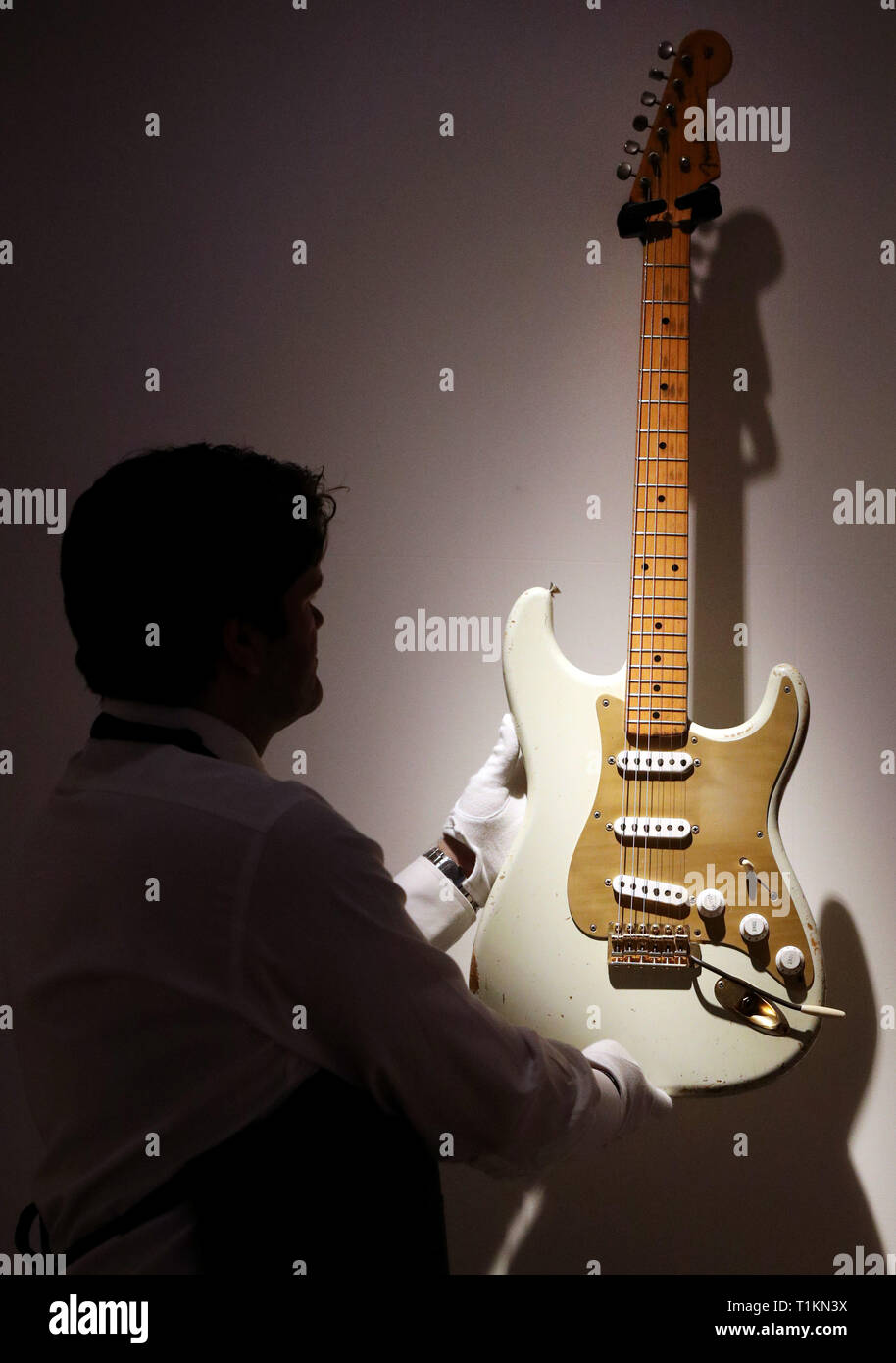 Un manutentionnaire berceaux la Fender Stratocaster white 1954, avec le numéro '0001', la guitare électrique solid body lors d'un aperçu de l'exposition préalable à la vente de la collection de guitare personnels de Pink Floyd David Gilmour, chez Christie's à Londres. Banque D'Images