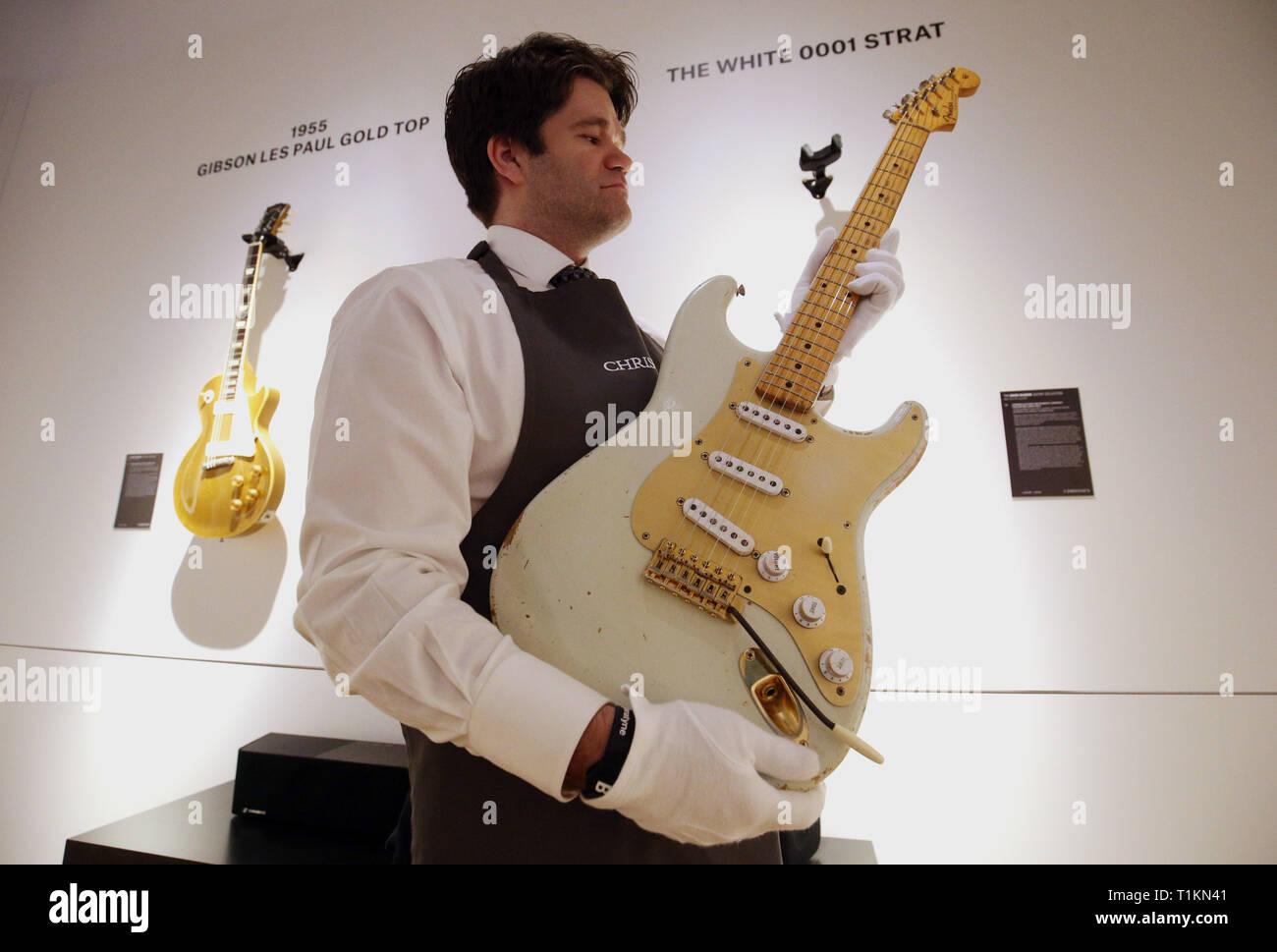 Un manutentionnaire berceaux la Fender Stratocaster white 1954, avec le  numéro '0001', la guitare électrique solid body lors d'un aperçu de  l'exposition préalable à la vente de la collection de guitare personnels