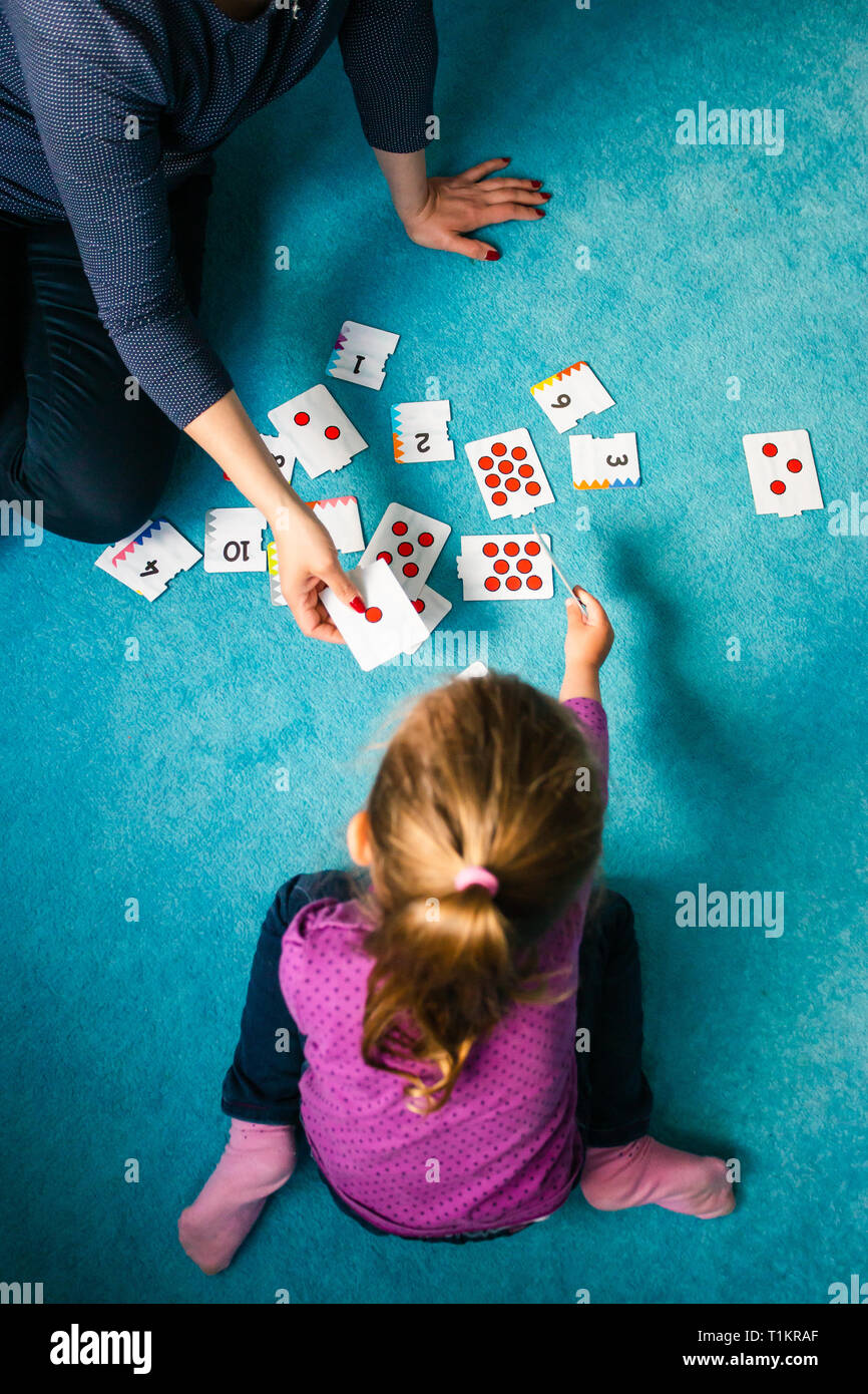 L'enseignement de mère en comptant sa petite fille à l'aide de jeu de carte assis sur un tapis à la maison Banque D'Images