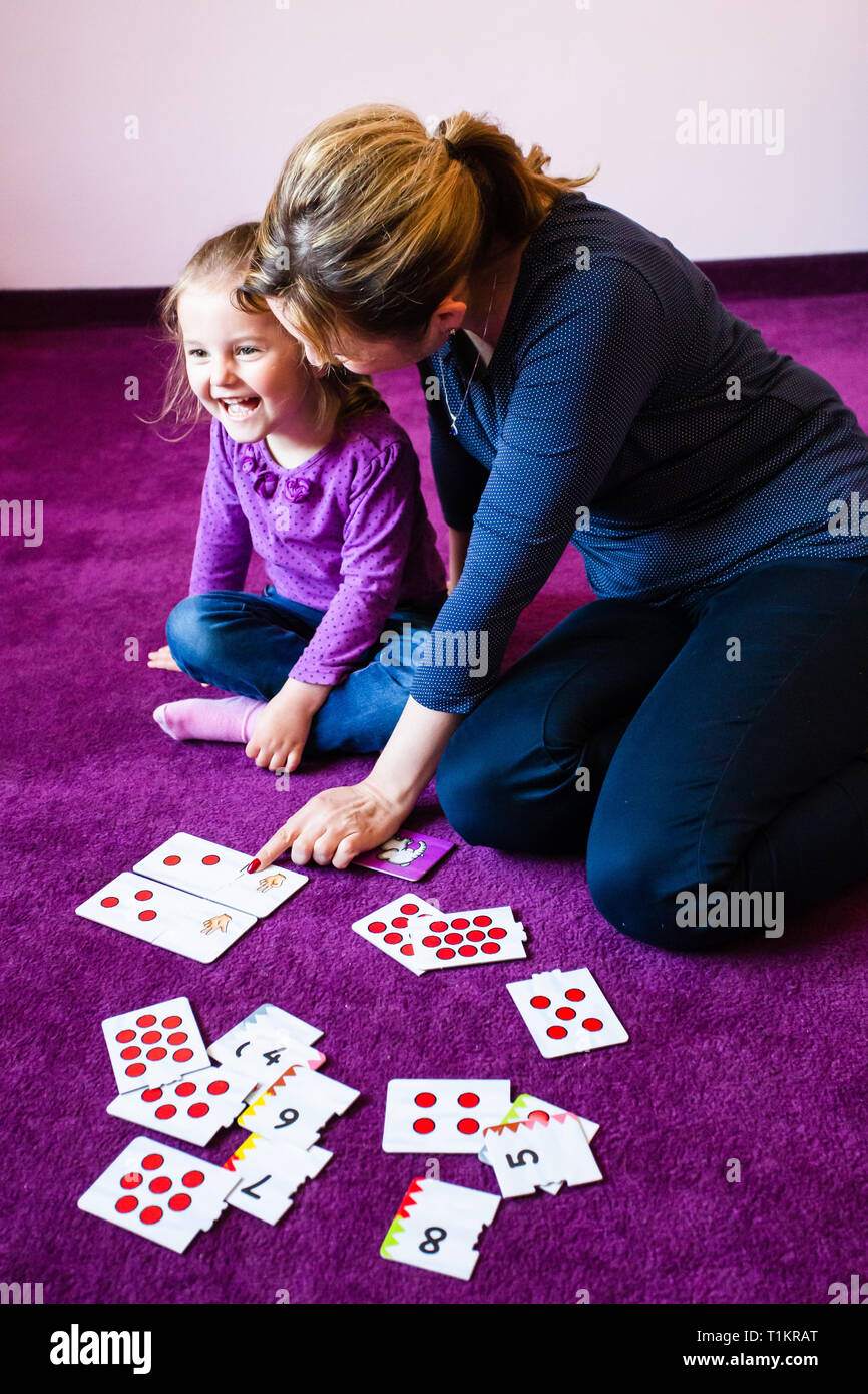 L'enseignement de mère en comptant sa petite fille à l'aide de jeu de carte assis sur un tapis à la maison Banque D'Images
