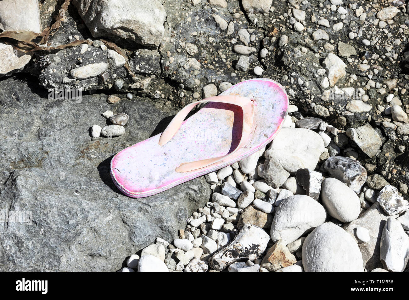 Un abandonné ou perdu rose chaussure de volte-face sur une plage de galets Banque D'Images