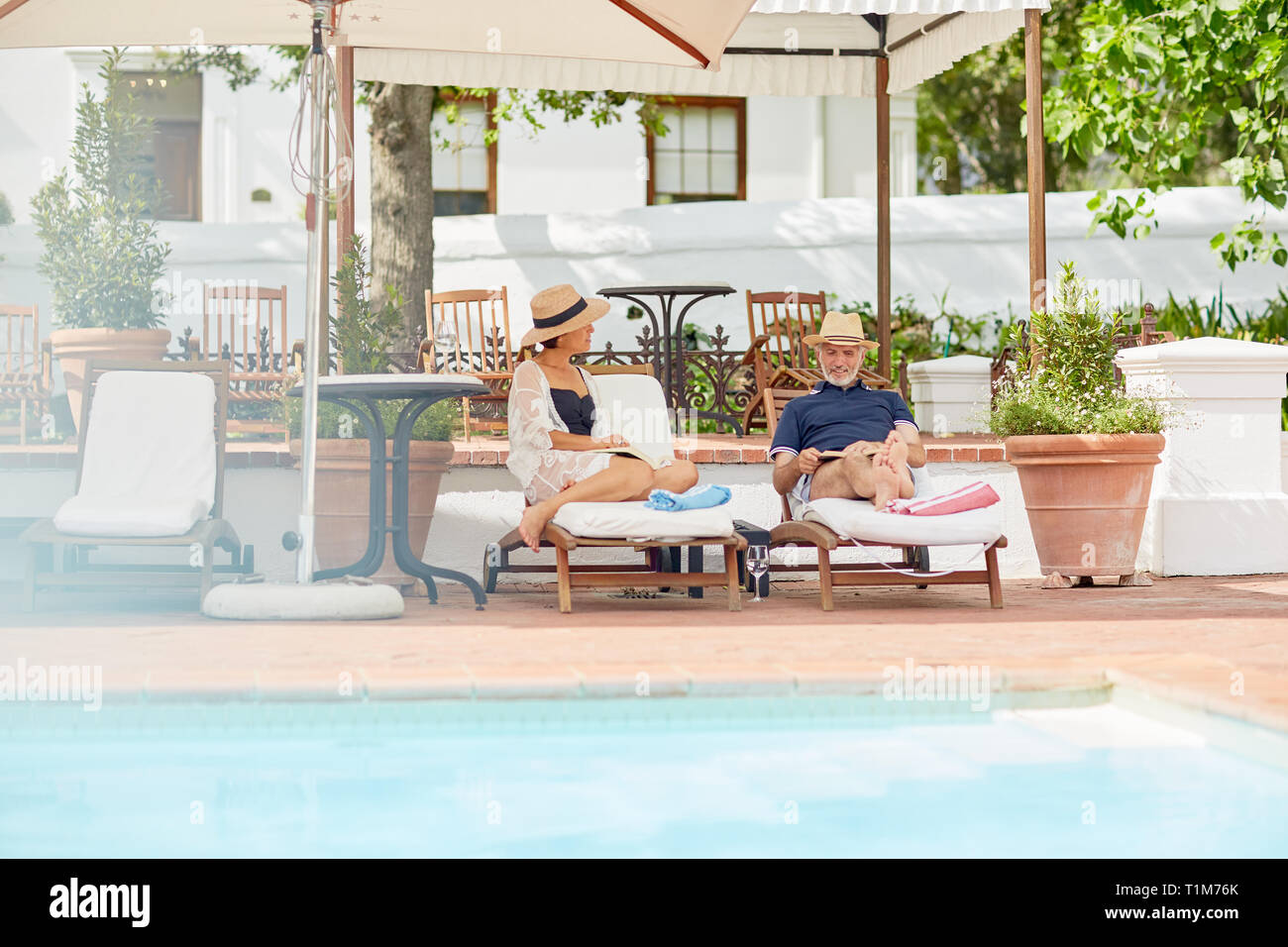 Young couple relaxing on lounge chairs at poolside resort Banque D'Images