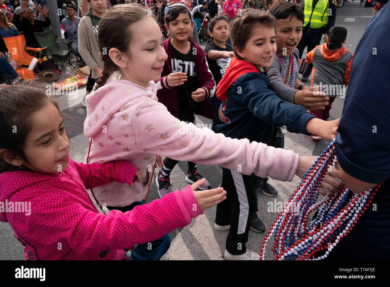 Les mains hors de bénévolat à perles de souvenirs des enfants sur le parcours au cours de l'anniversaire de Washington annuel défilé fête au centre-ville de Laredo, Texas. Banque D'Images
