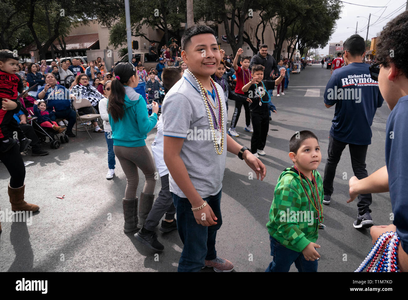 Les mains hors de bénévolat à perles de souvenirs des enfants sur le parcours au cours de l'anniversaire de Washington annuel défilé fête au centre-ville de Laredo, Texas. Banque D'Images