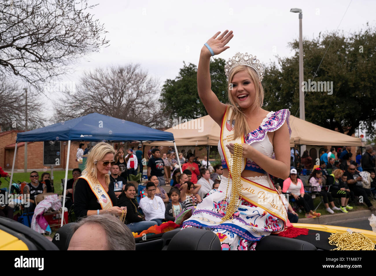 Young woman wearing crown se trouve à l'arrière de la voiture décapotable et les vagues de foule pendant l''année de l'Anniversaire de Washington parade en Laredo TX USA Banque D'Images