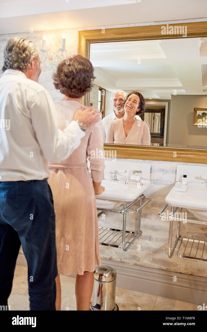Mature couple standing at hotel miroir de salle de bains Banque D'Images