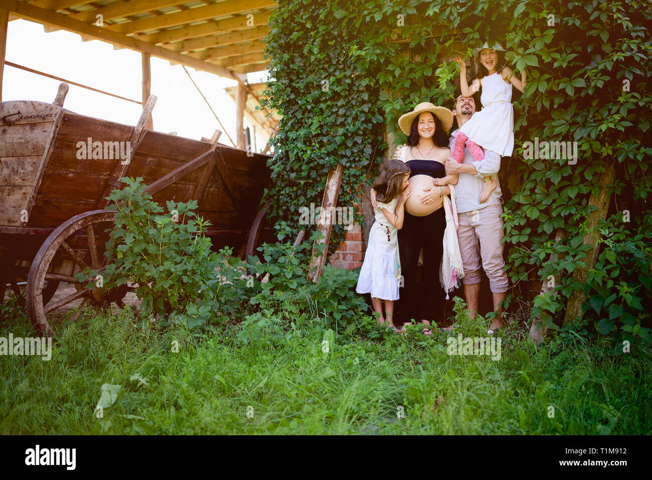 Portrait de la famille enceinte dans le jardin rural Banque D'Images