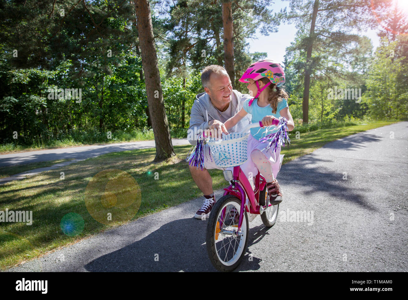 L'enseignement du père sa fille à circuler à bicyclette. Happy kid learning riding bike. Famille de passer du temps ensemble. Journée ensoleillée sur suburb street. Banque D'Images