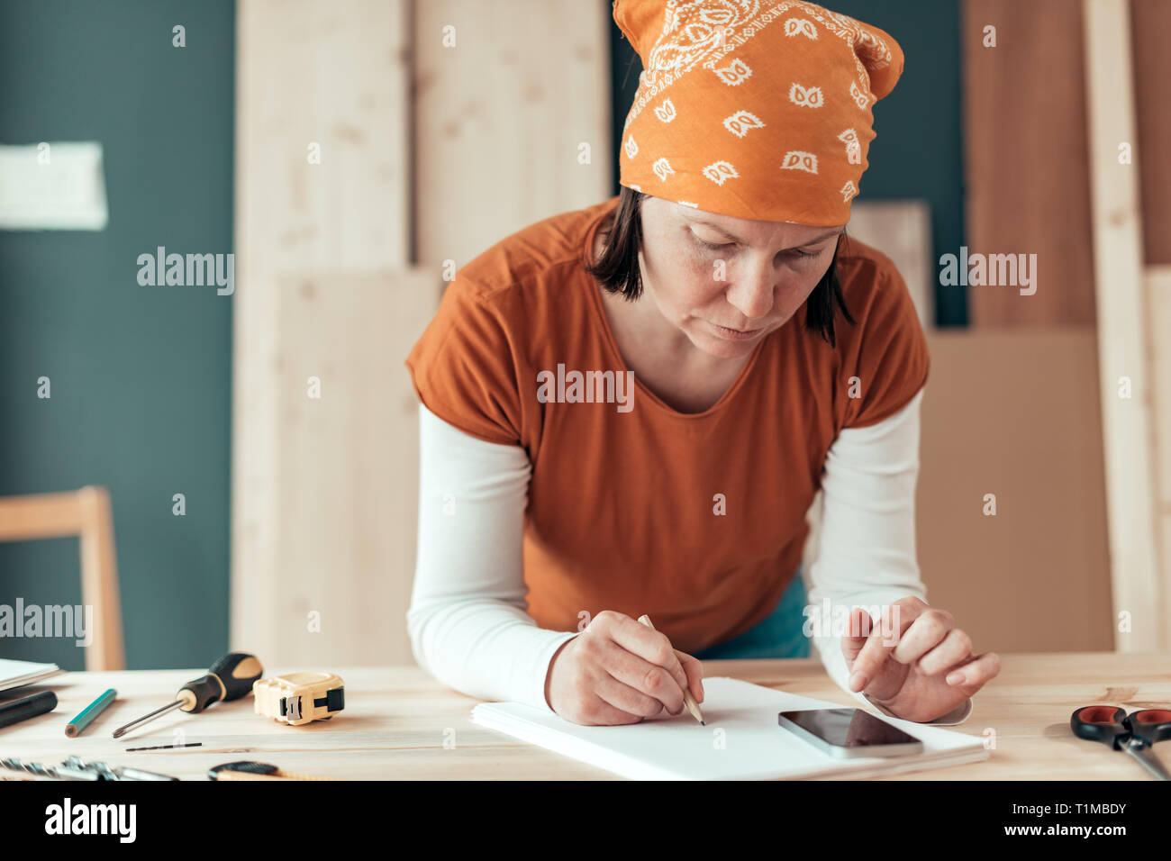 Female carpenter avec foulard tête faisant calcul financier dans l'atelier de menuiserie menuiserie Banque D'Images