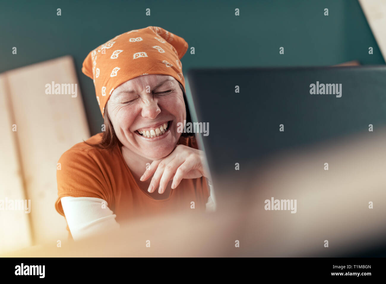 Happy smiling female carpenter lors de chat en ligne avec le client sur un ordinateur portable dans l'atelier de menuiserie Banque D'Images
