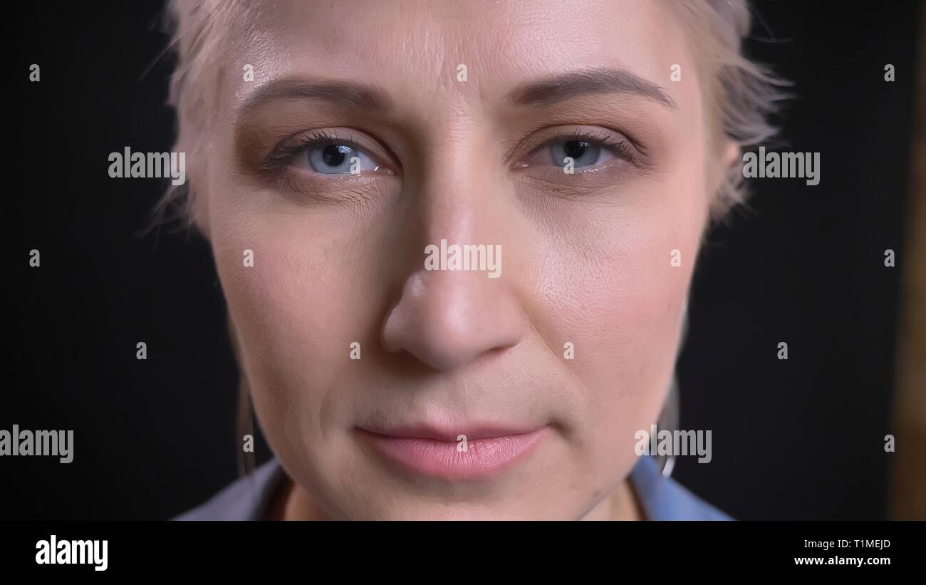 L'analyse de young attractive Gros plan femme de race blanche aux cheveux blonds et aux yeux bleus regardant droit dans la caméra. Banque D'Images