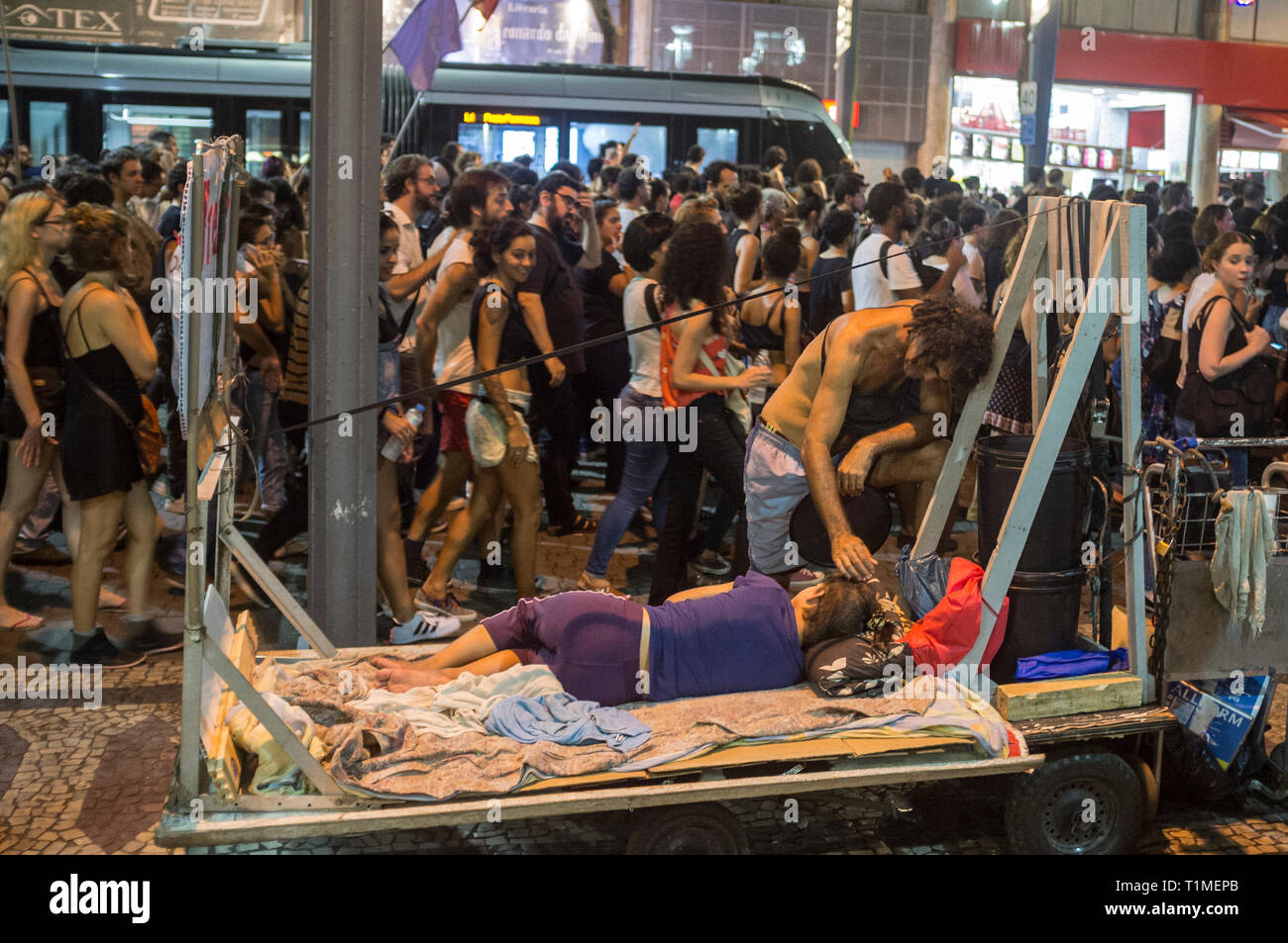 Démonstration pour Marielle Franco, homme politique brésilien, féministe et militante des droits de l'homme, assassiné le 14 mars 2018 à Rio de Janeiro - elle avait été un critique virulent de brutalités policières et d'exécutions extrajudiciaires dans la ville. Les manifestants passent par travailleur de rue qui prend soin de son partenaire malade, le centre-ville de Rio de Janeiro, Brésil. Banque D'Images