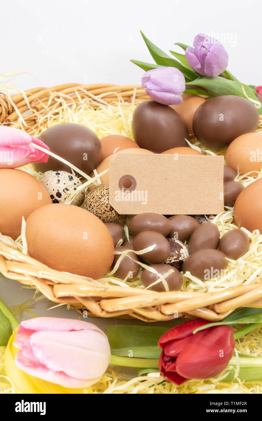 Ressources graphiques avec étiquette vierge dans le panier de Pâques avec des oeufs et des tulipes Banque D'Images