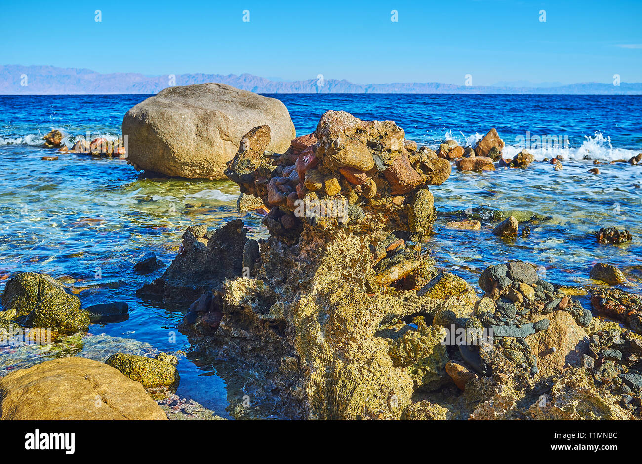 Les marins du golfe d'Aqaba, avec une vue sur bouldrs, squelette de corail et l'ondulation sur la surface de l'eau d'un bleu profond, le Sinaï, en Égypte. Banque D'Images