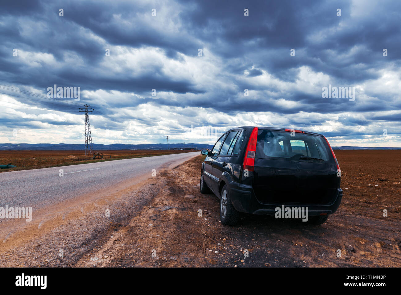 Broken voiture s'est arrêtée par la route le jour de tempête, dramatique nuages sur le ciel Banque D'Images