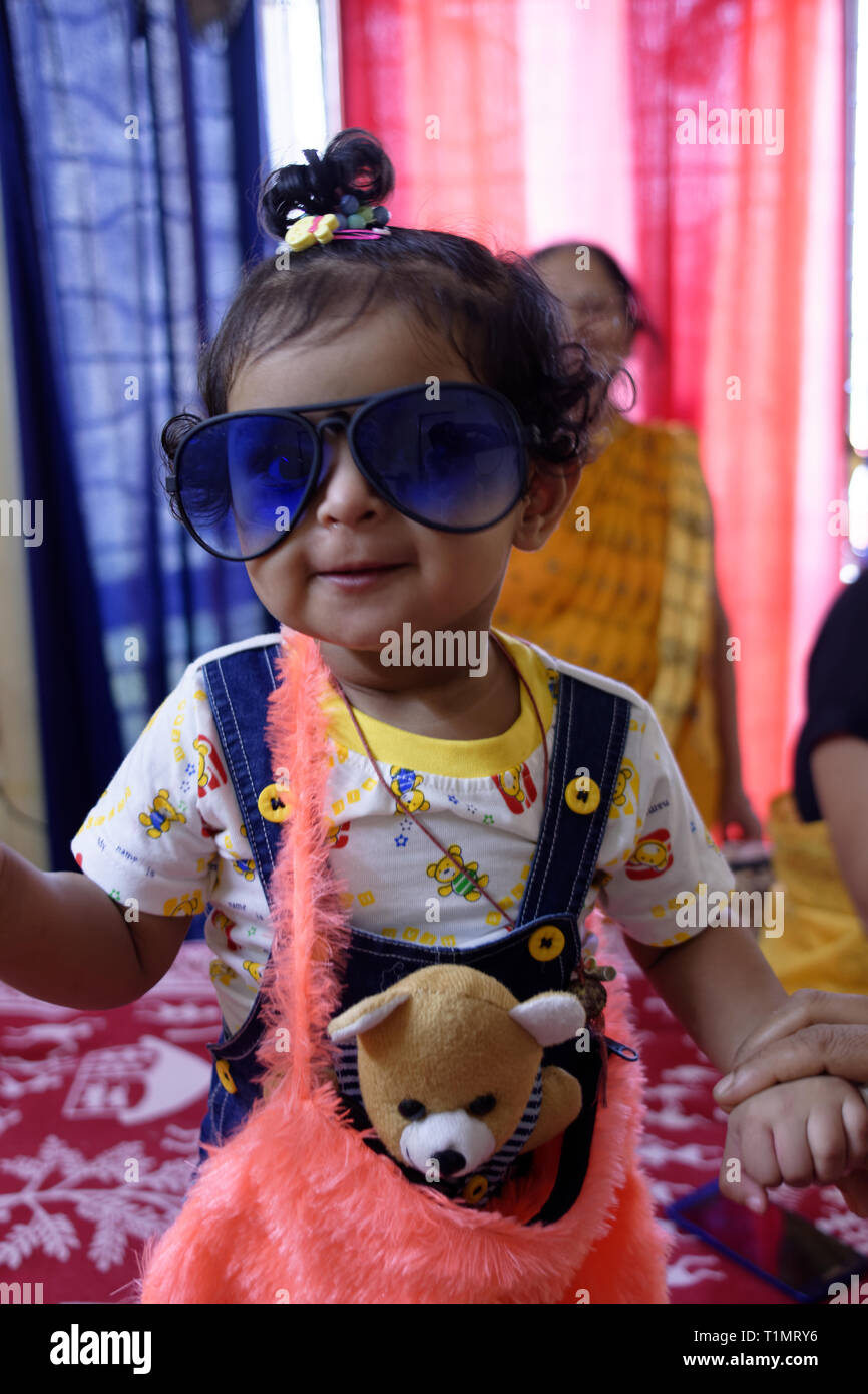 Un beau bébé enfant fille indienne posant dans un drôle d'humeur portant un  grand soleil bleu le verre dans un environnement accueillant Photo Stock -  Alamy