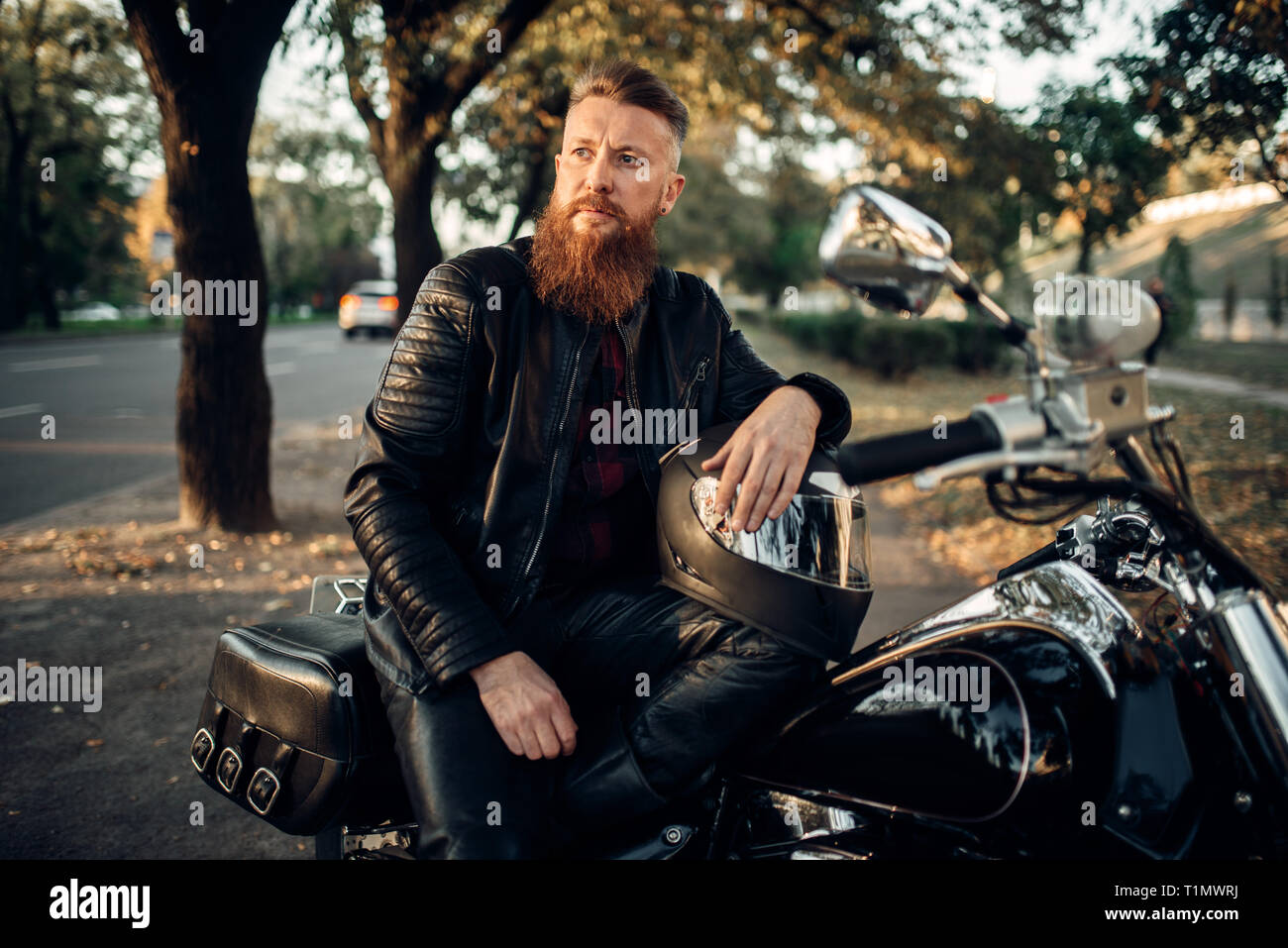 Biker assis sur le sol contre son chopper Banque D'Images