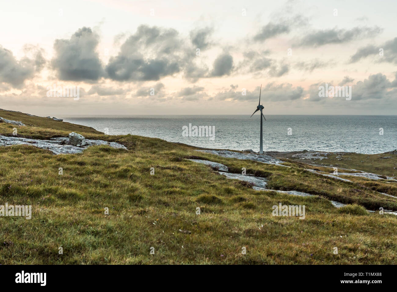 Éolienne au coucher du soleil dans un magnifique paysage écossais, à l'île de Barra, îles Hébrides, Ecosse, Royaume-Uni Banque D'Images
