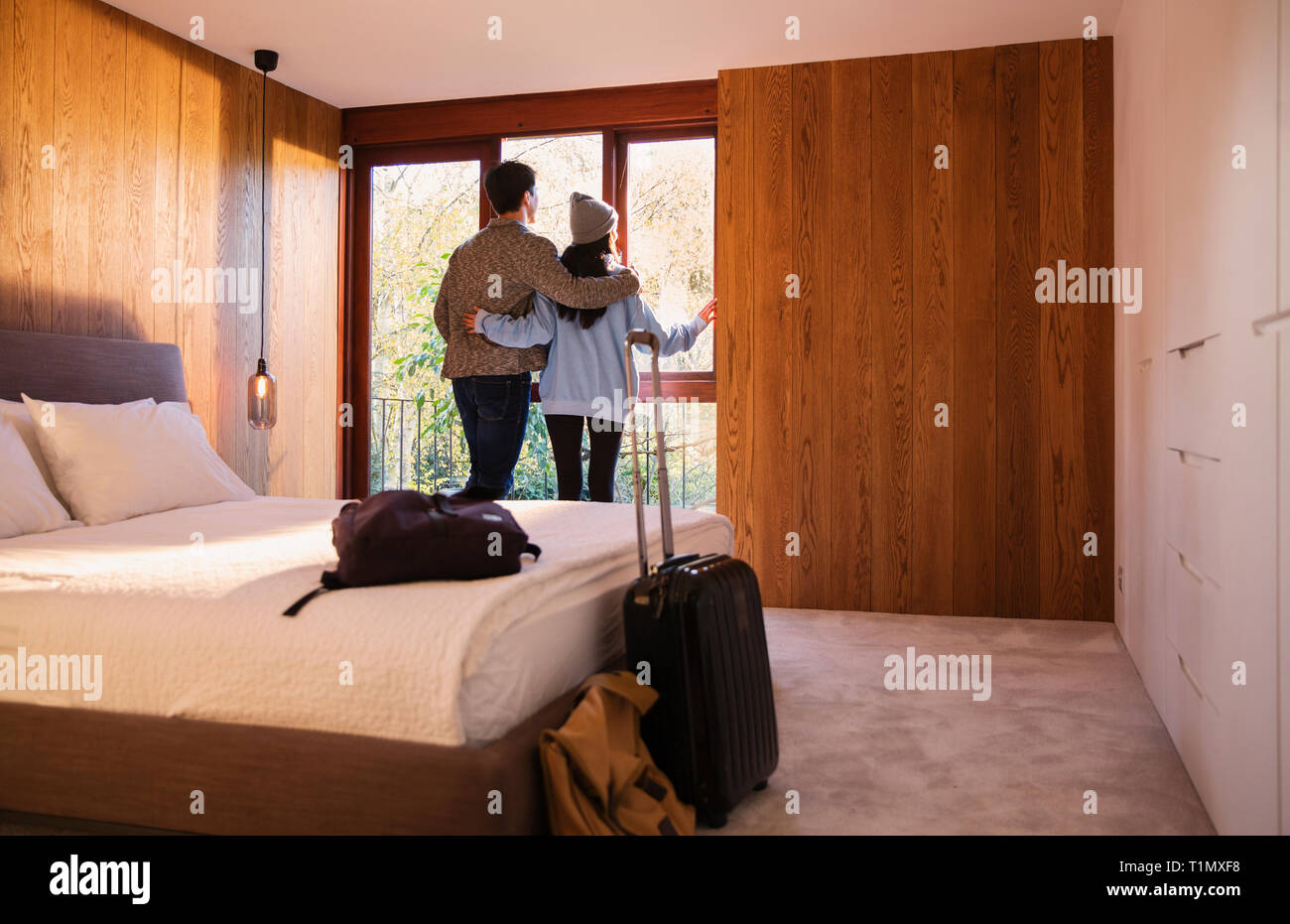 Couple avec valise à la fenêtre de la chambre à Banque D'Images