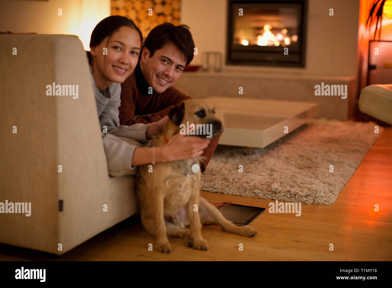 Portrait couple heureux avec le chien dans la salle de séjour Banque D'Images
