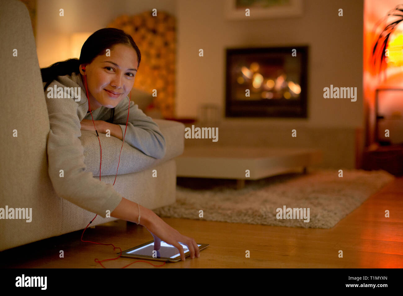 Portrait of smiling young woman listening to music with headphones and digital tablet Banque D'Images