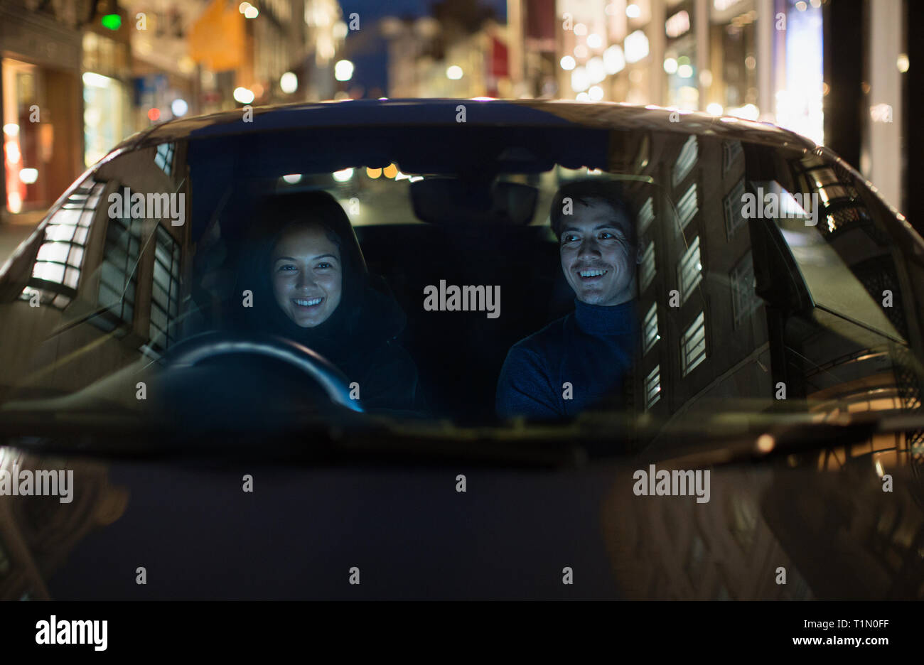 Smiling couple driving on city street Banque D'Images