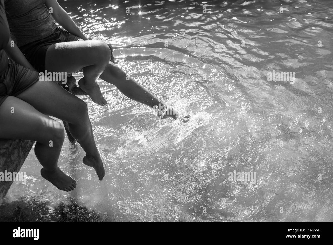 Mère et fille splashing pieds de sunny river Banque D'Images