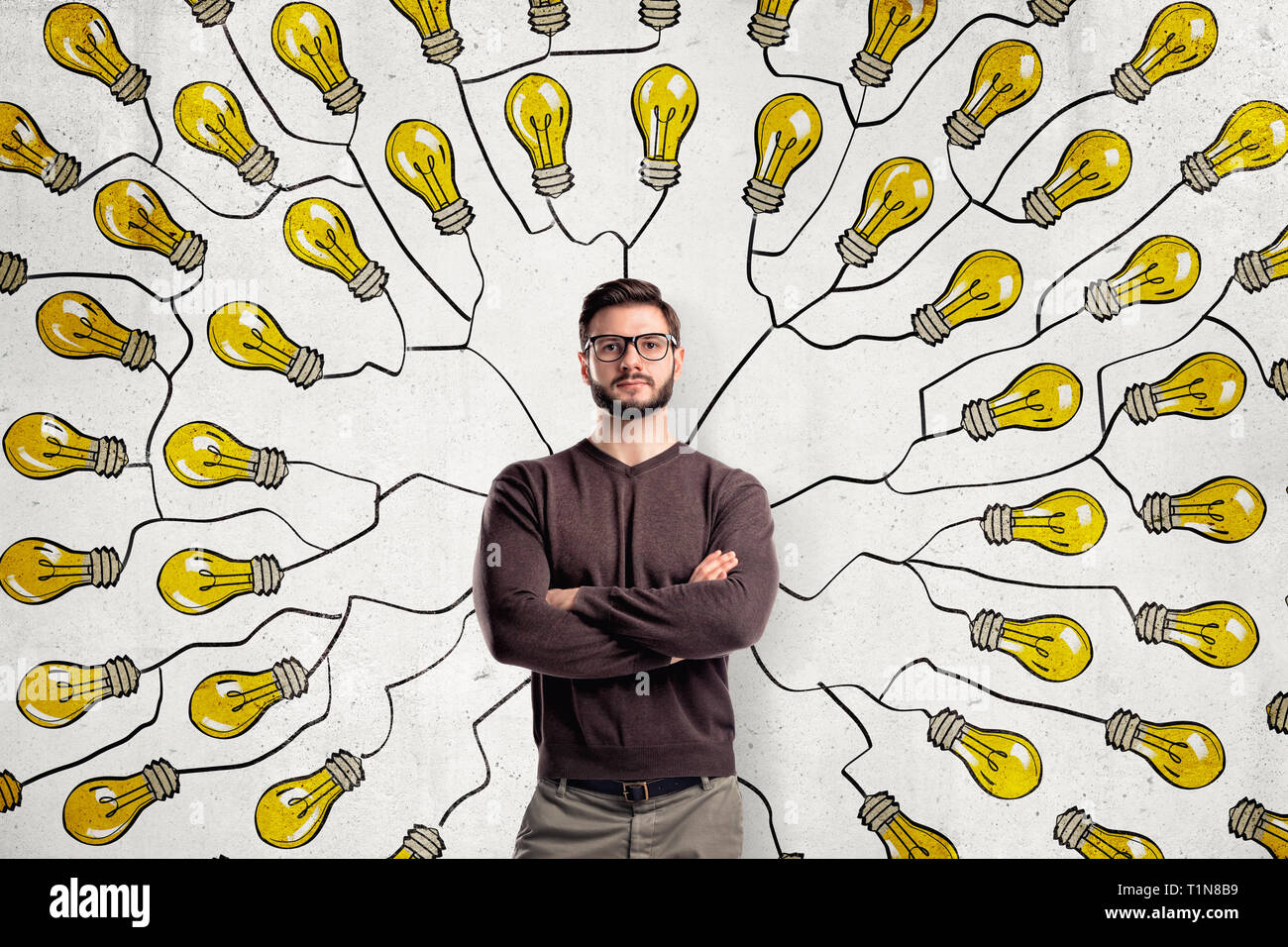 Jeune homme avec des lunettes portant des vêtements décontractés sur fond d'ampoules jaunes Banque D'Images