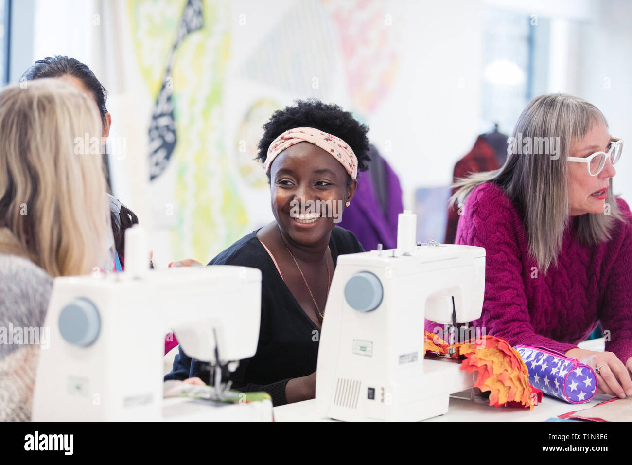 Happy female fashion designer, parler avec tes collègues à la machine à coudre Banque D'Images