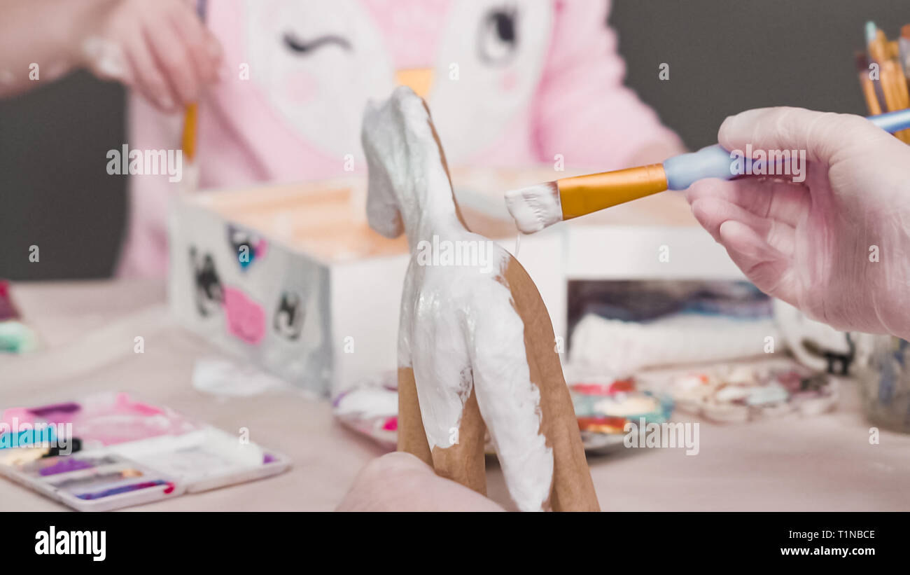 Peindre avec une peinture acrylique blanche licorne figurine en papier mâché. Banque D'Images