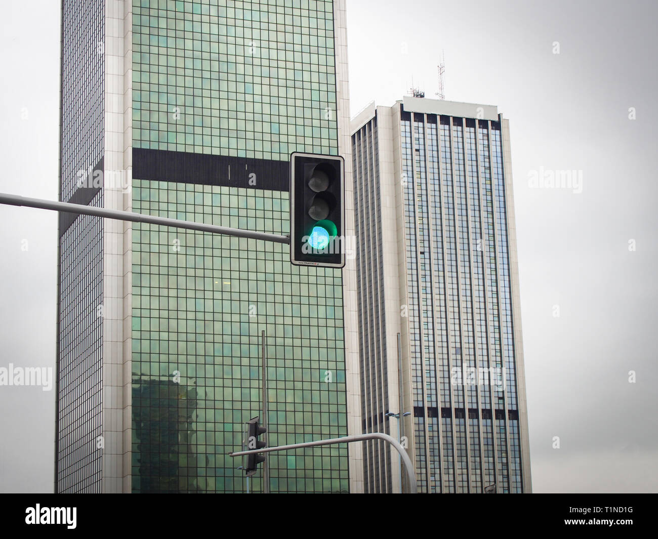 Feu avec le feu vert sur les gratte-ciel, sur le fond, ciel nuageux Banque D'Images