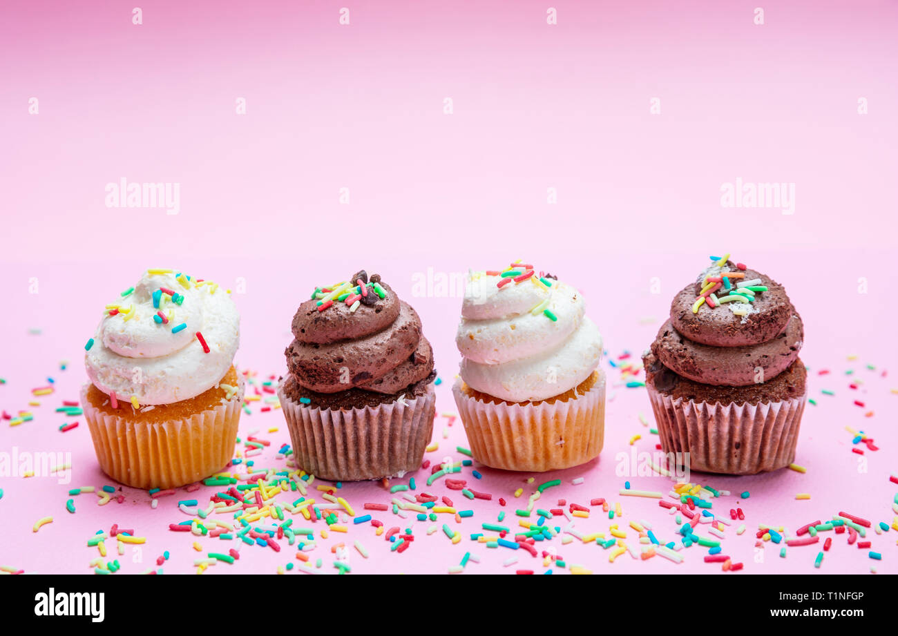 Cupcakes sur fond rose. Quatre cupcakes vanille et chocolat avec des Sprinkles, copy space Banque D'Images