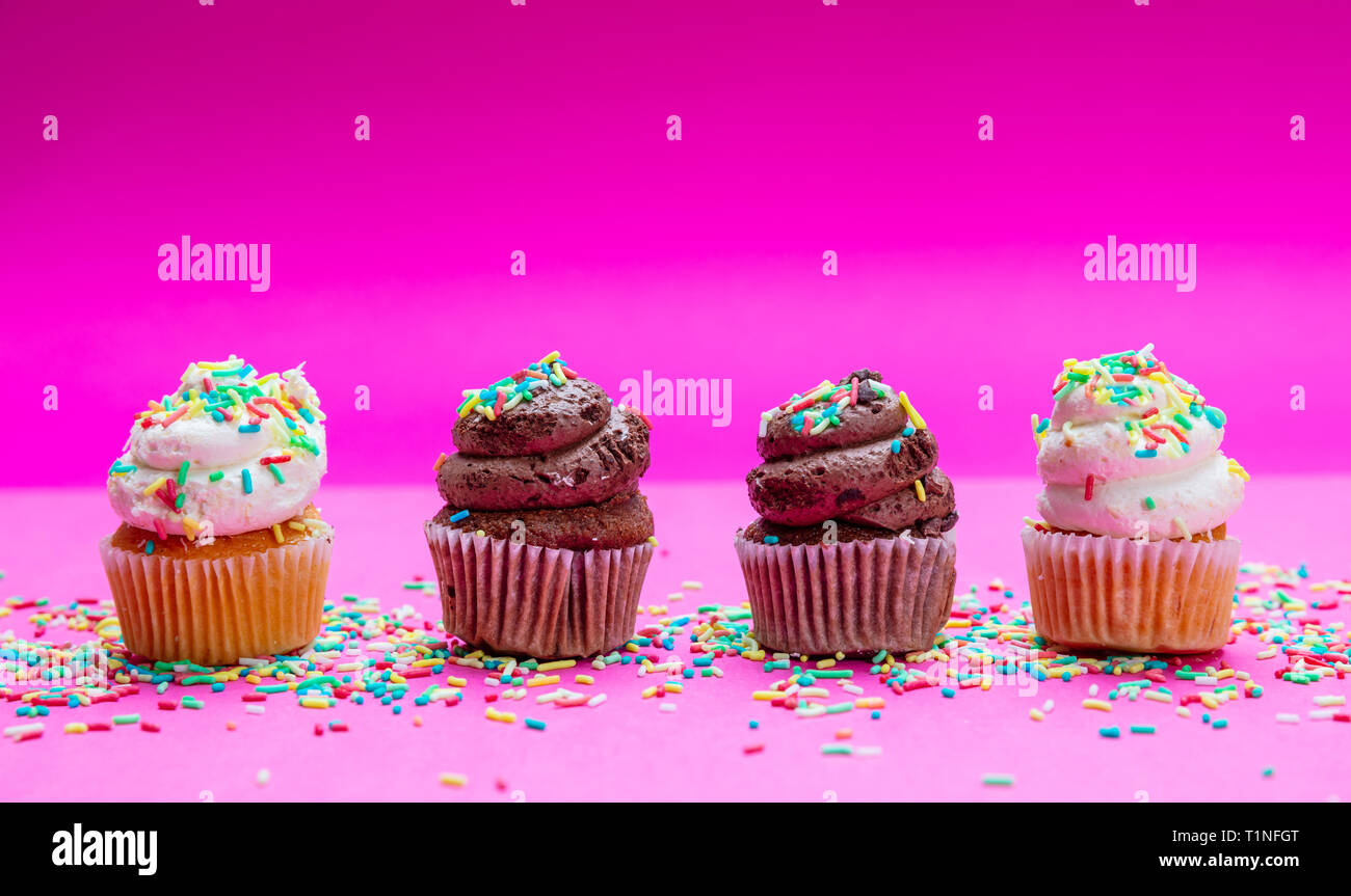 Cupcakes sur fond rose vif. Quatre cupcakes vanille et chocolat avec des Sprinkles, copy space Banque D'Images