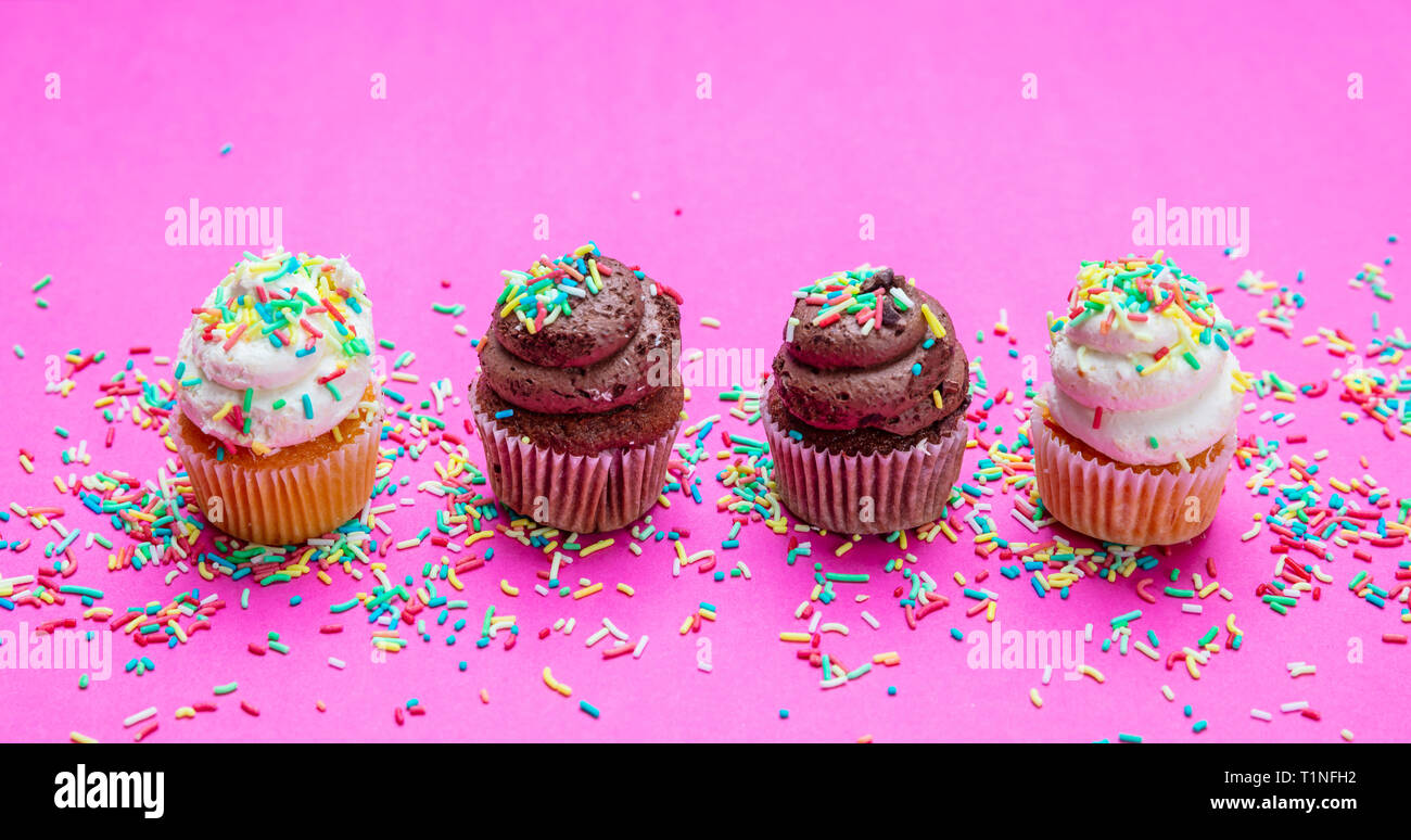 Cupcakes sur fond rose vif. Quatre cupcakes vanille et chocolat avec des Sprinkles, vue rapprochée Banque D'Images